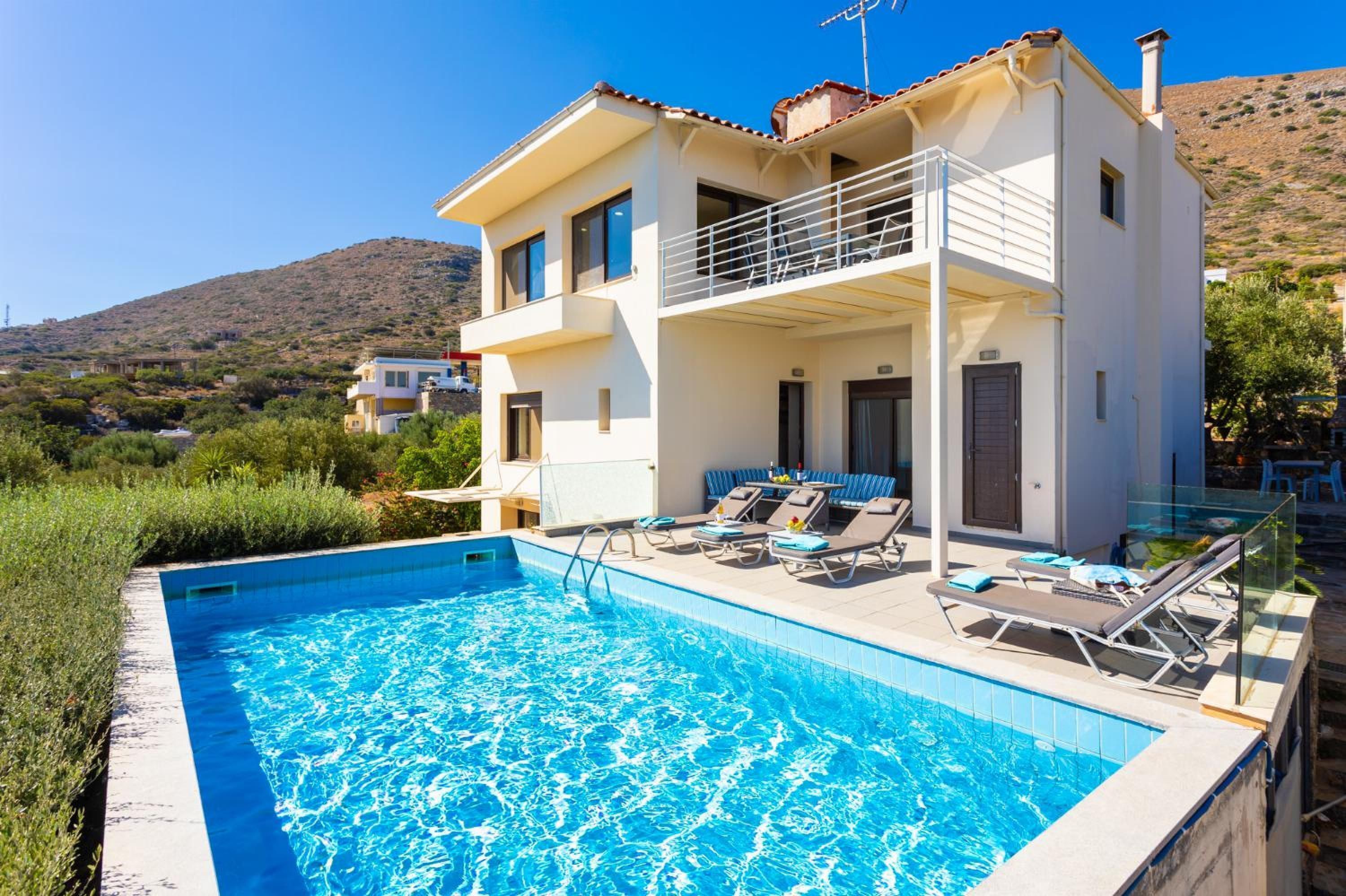 A two-story building with a swimming pool, a balcony, and a view of the surrounding landscape.
