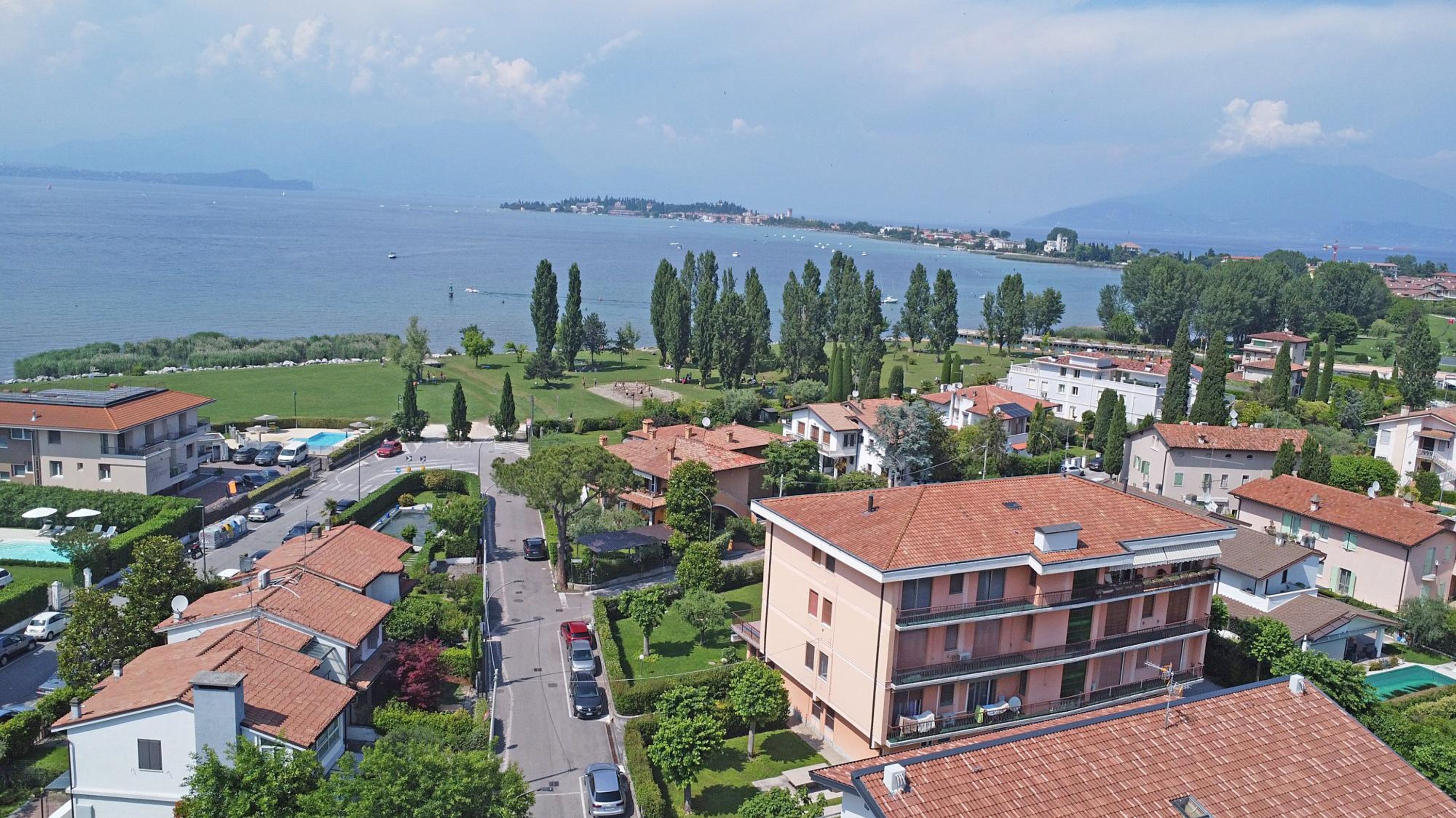 Et boligområde med huse, en vej og et vandareal i baggrunden.