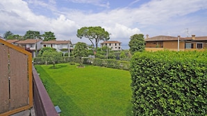 A residential area with a well-maintained lawn, a large tree, and houses with red-tiled roofs. - Appartamento Brema in Sirmione (Sirmione)