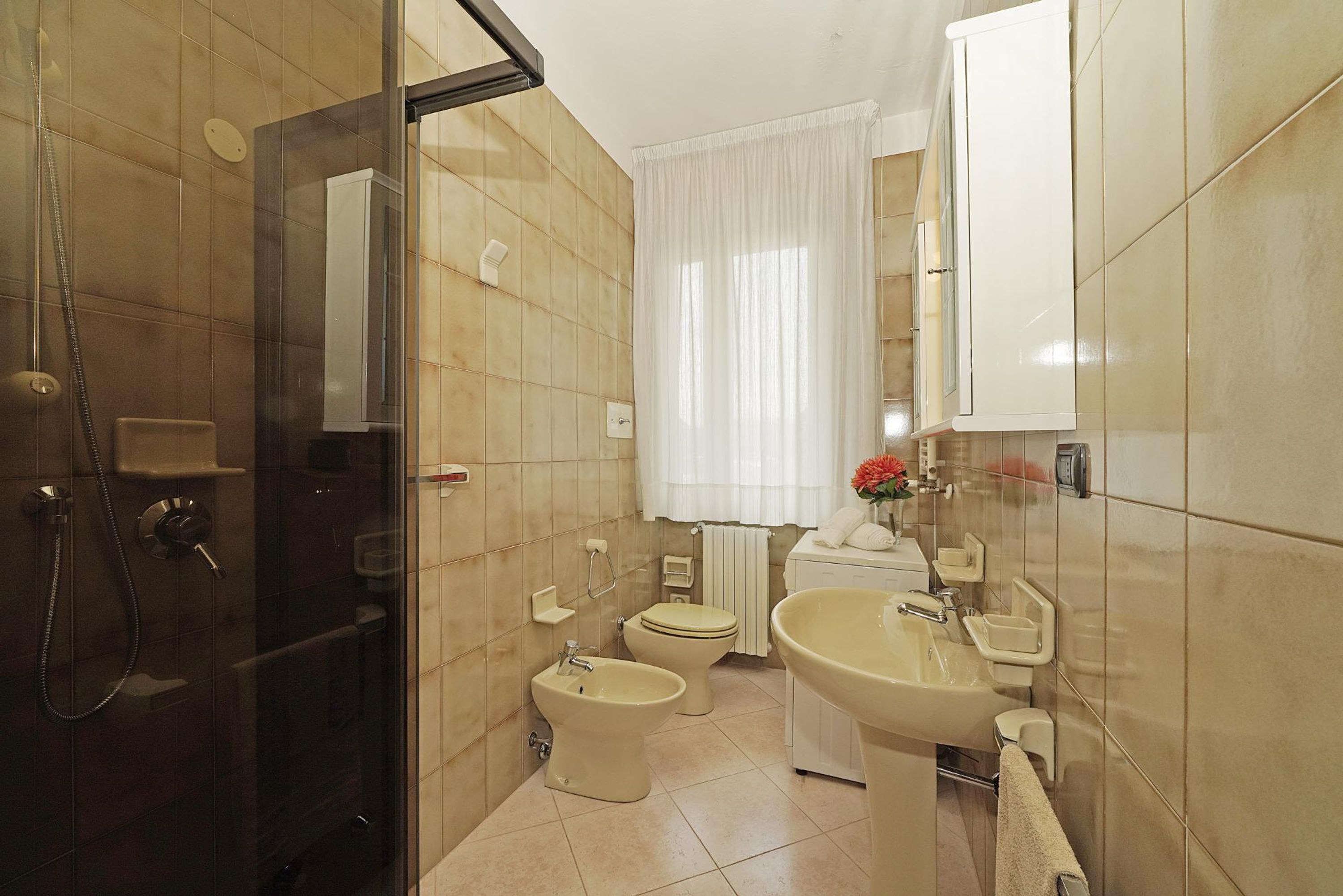 Une salle de bain équipée d’une douche, d’un bidet, de toilettes, d’un lavabo et d’un miroir.