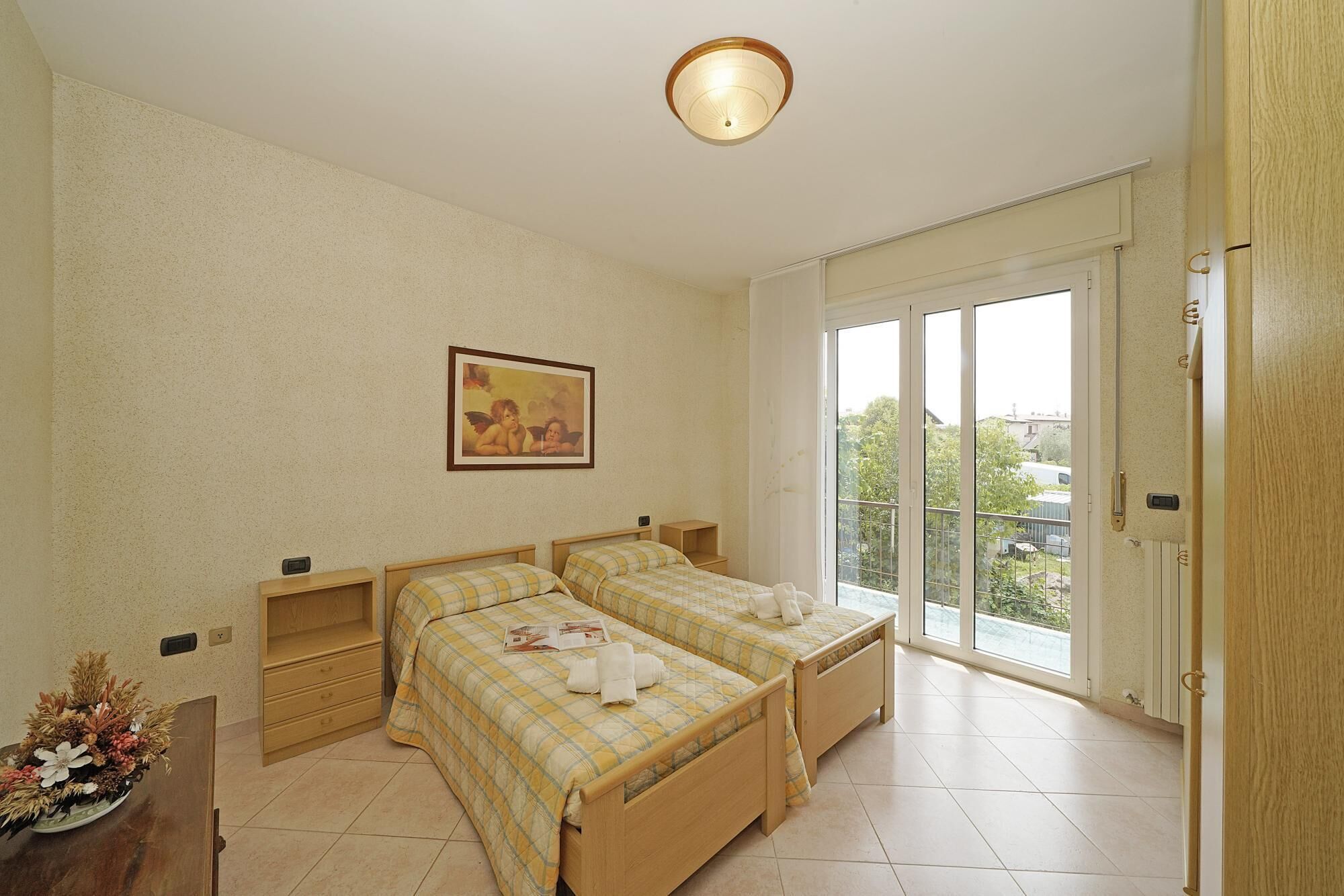 Een slaapkamer met twee bedden, een schilderij, een kleine tafel en een raam met uitzicht.