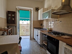 Une cuisine équipée d’une cuisinière à gaz, d’un four, d’un four à micro-ondes et d’une fenêtre donnant sur un balcon.