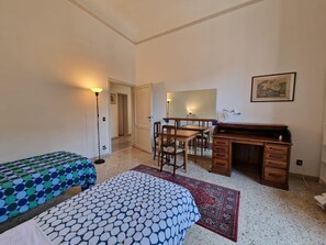 Une chambre avec deux lits, un bureau, une chaise, une lampe et un tapis.
