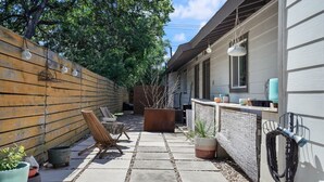 A patio area with a stone pathway, outdoor furniture, potted plants, and a hanging light fixture. - Stylish Austin Retreat w/ Luxurious King Bed + W/D (Austin)