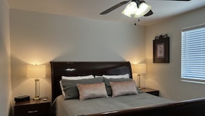 Una camera da letto con un letto, due comodini, una ventola a soffitto e una finestra con tende.