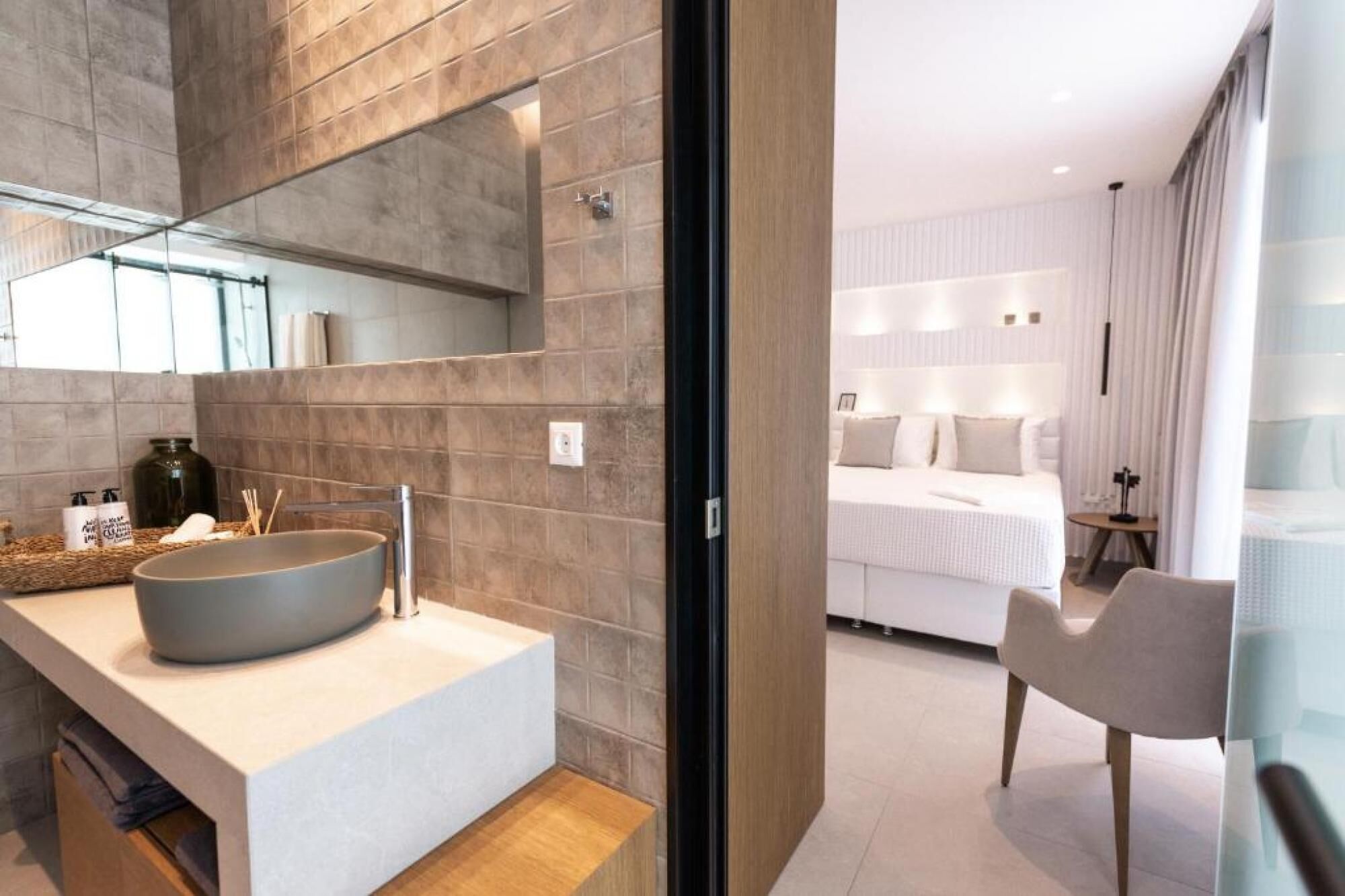 Une salle de bain moderne avec un grand lavabo sur pied, un miroir et des articles de toilette posés sur le comptoir.