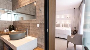 Une salle de bain moderne avec un grand lavabo sur pied, un miroir et des articles de toilette posés sur le comptoir.