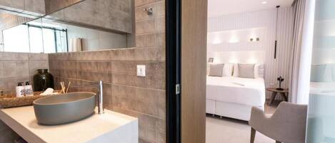 Une salle de bain moderne avec un grand lavabo sur pied, un miroir et des articles de toilette posés sur le comptoir.