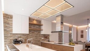 Une cuisine moderne dotée d’un îlot central, de tabourets de bar et d’un mur d’accent en pierre.