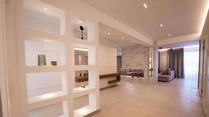 Un vaste espace de vie agrémenté d’un mur en marbre, d’un canapé et d’une table basse. Des étagères intégrées accueillent des objets décoratifs.