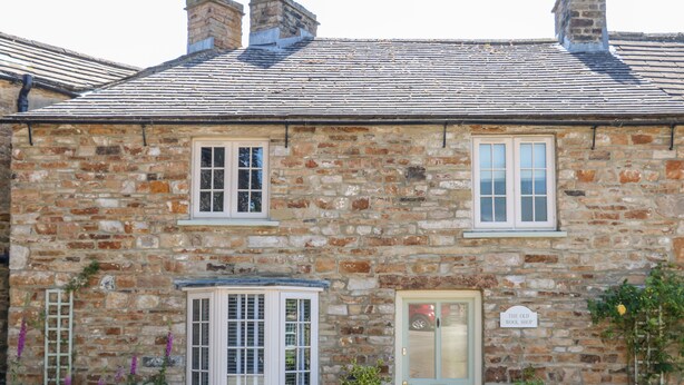 A stone building with a traditional design, featuring a bay window, a front door, and a small shop sign. - Old Wool Shop (Leyburn)