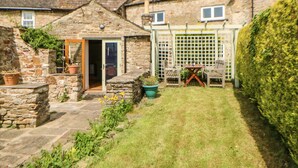 A stone house with a small garden, a wooden door, and a white fence. - Old Wool Shop (Leyburn)