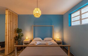 Quarto com cama, abajures, cabeceira de madeira, janela e uma planta.