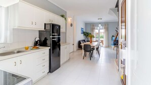 Et moderne køkken med hvide skabe, et sort køleskab og et spiseområde med et bord og stole.