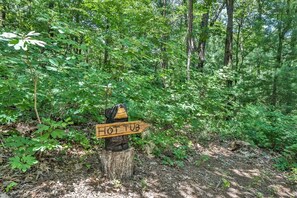 A wooden sign with 'HOT TUB' written on it, surrounded by dense green foliage. - Bear Necessities | Ellijay, GA (Ellijay)