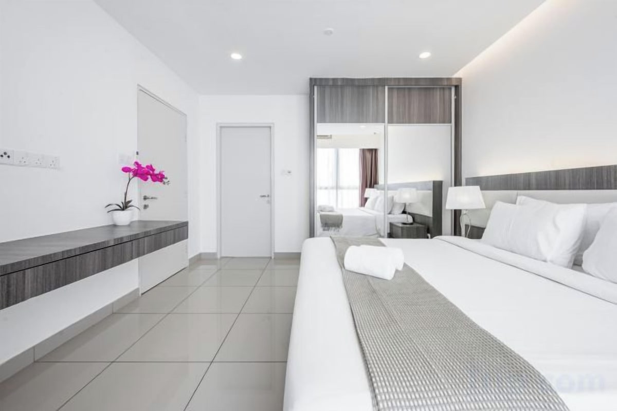 Ein modernes Hotelzimmer mit einem großen Bett, einem Nachttisch, einem Spiegel und einer Tür zu einem Badezimmer.