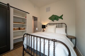Un dormitorio con cama, armario, decoración de pez verde en la pared y mesita de noche.