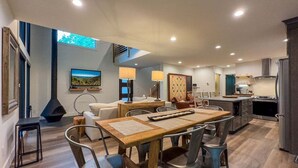 Eine moderne Küche mit einer zentralen Kochinsel, eingebauten Geräten und einem Essbereich mit Holztisch und Metallstühlen.