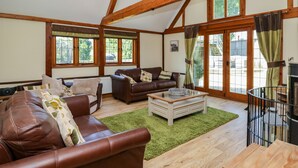 A spacious living room with wooden beams, leather sofas, a coffee table, and large windows with curtains. - Awelfan (Newtown)