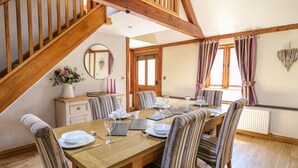 A dining room with a wooden table set for six, striped chairs, a wooden staircase, and a mirror on the wall. - Awelfan (Newtown)