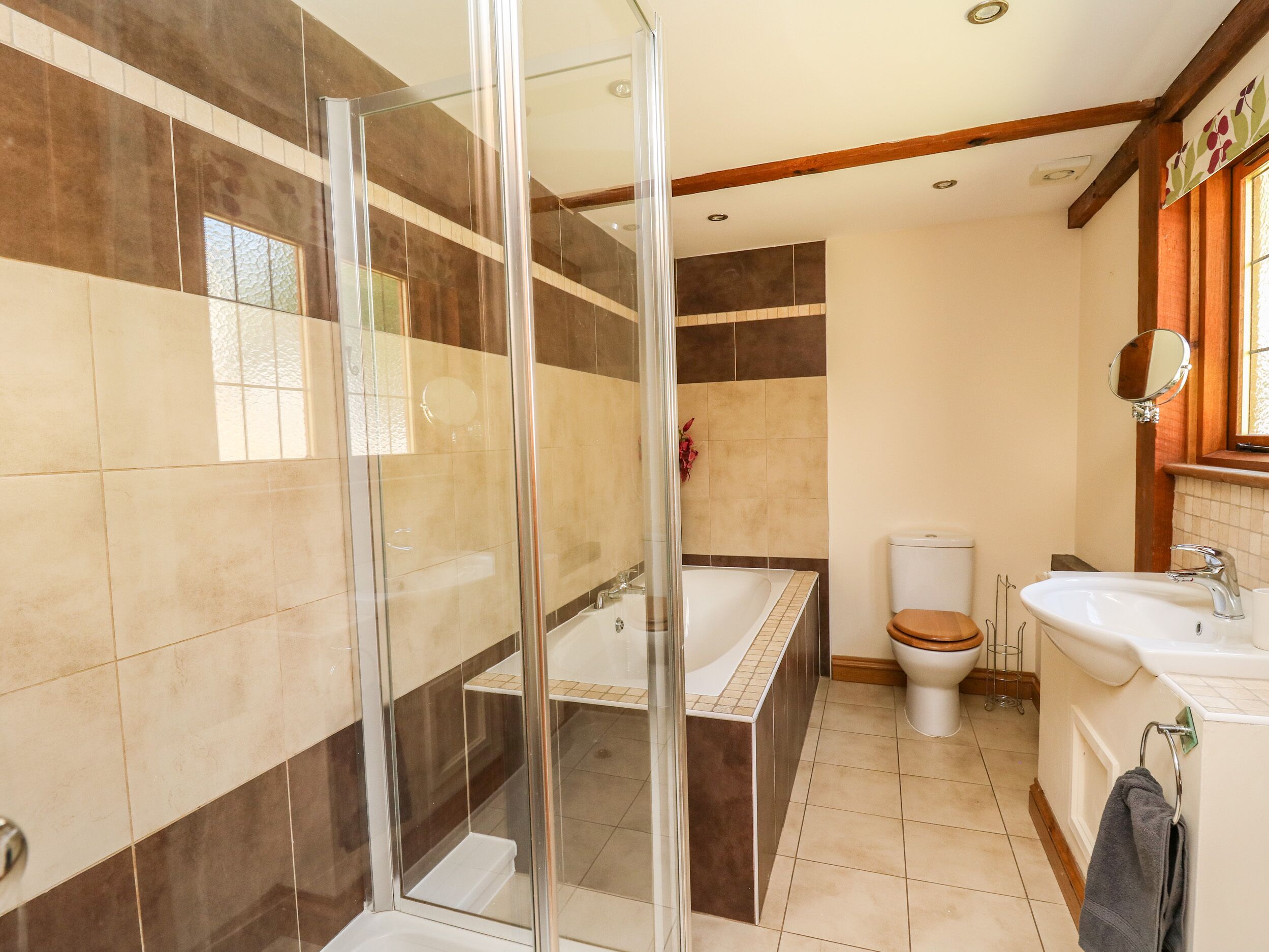 A bathroom with a glass-enclosed shower, a bathtub, a toilet, and a sink.