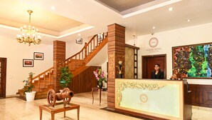 A hotel lobby with a grand staircase, a reception desk, and a chandelier. - Foxoso Misty Oaks Resort (Nainital)