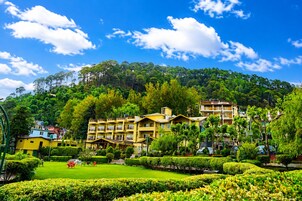 A hotel with multiple floors, surrounded by lush greenery and a well-maintained garden.