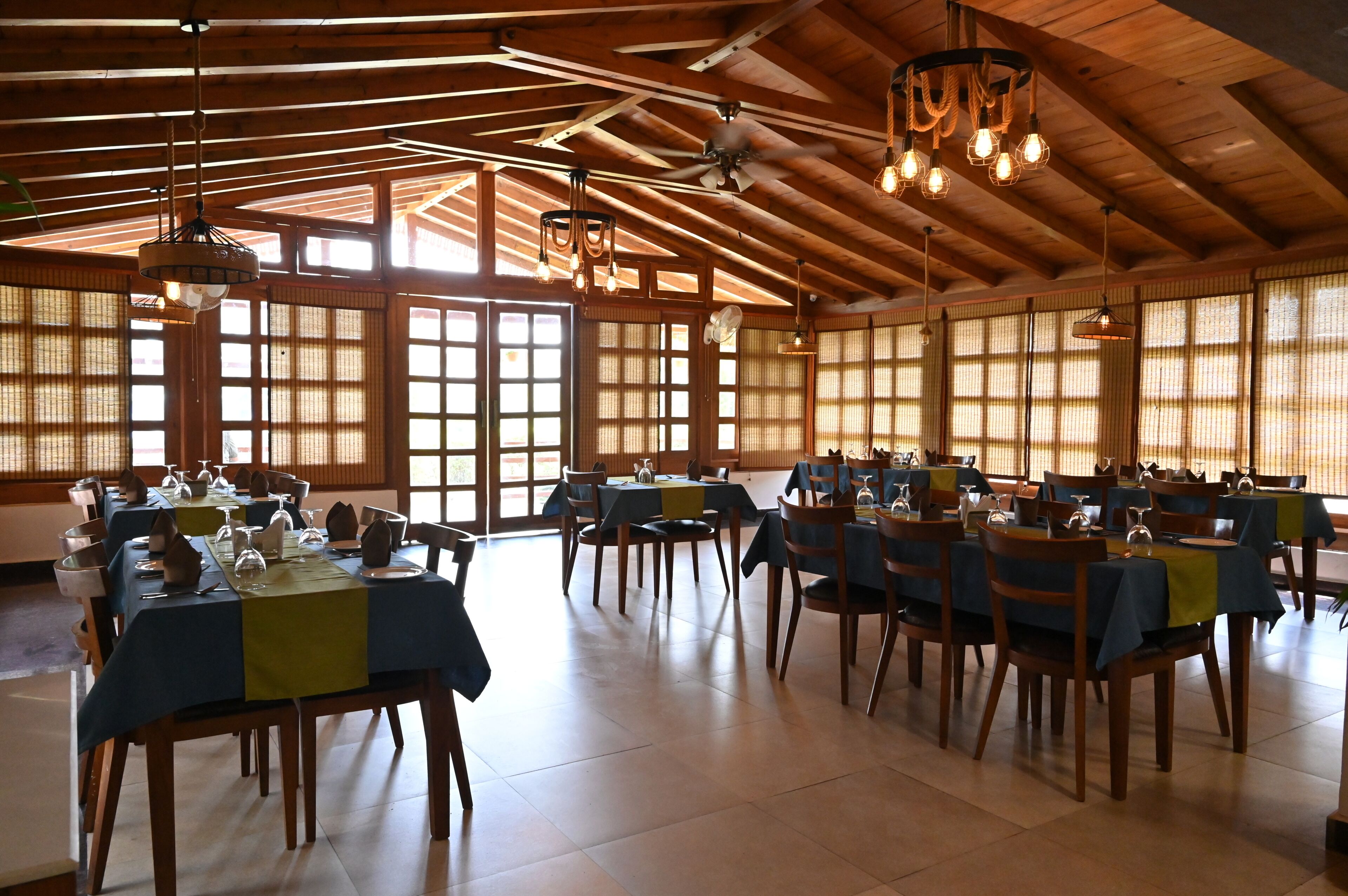 A spacious dining area with multiple tables, chairs, and hanging light fixtures.