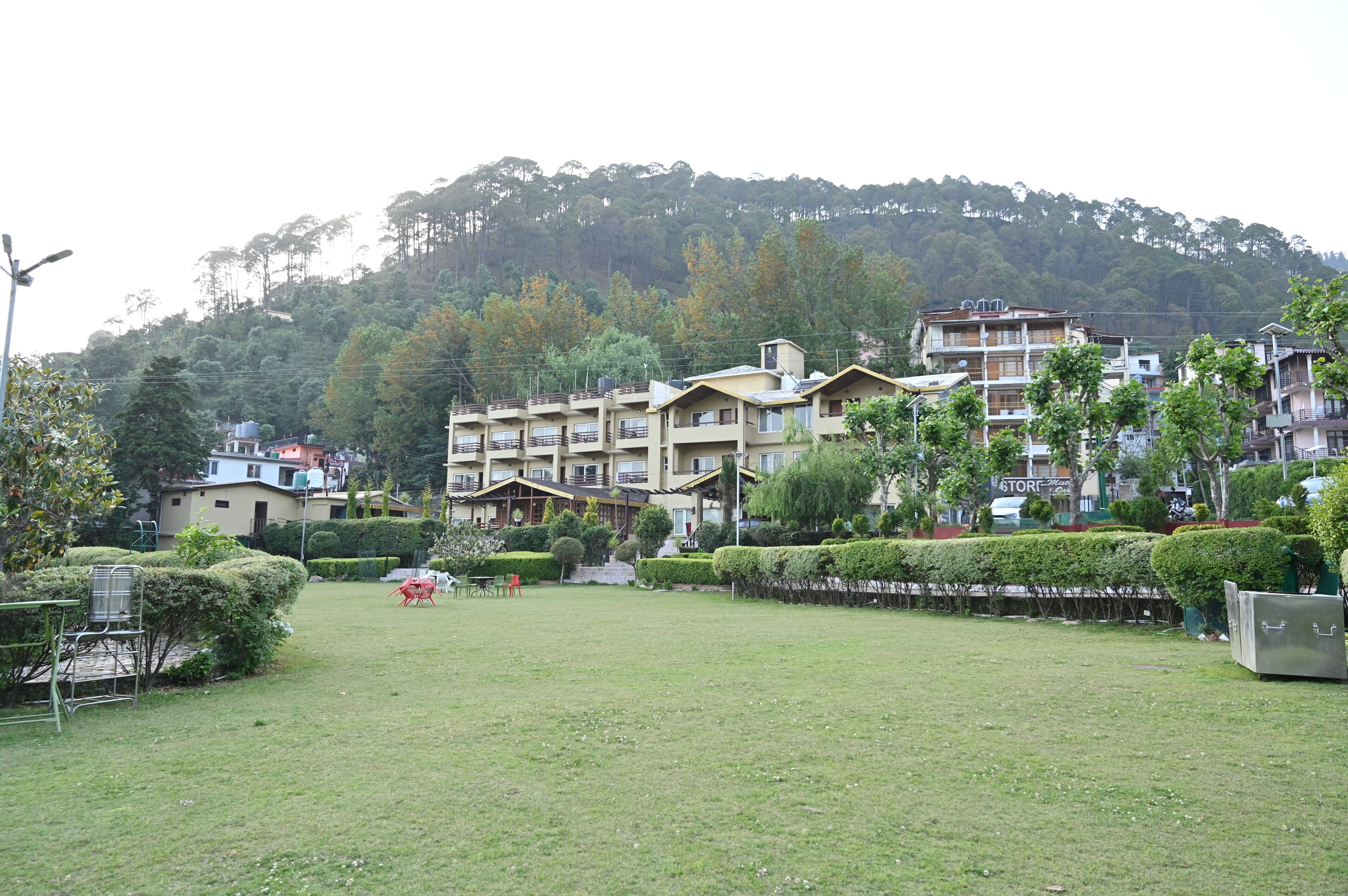 A residential area with multi-story buildings, a grassy courtyard, and a hill in the background.