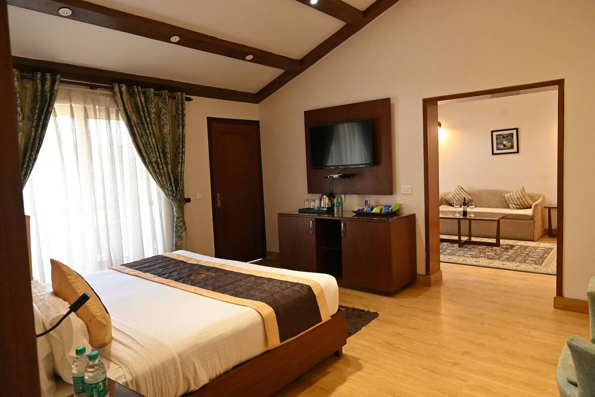 Une chambre d’hôtel dotée d’un grand lit, d’un téléviseur fixé au mur, d’un bureau et d’un canapé dans l’espace salon attenant.