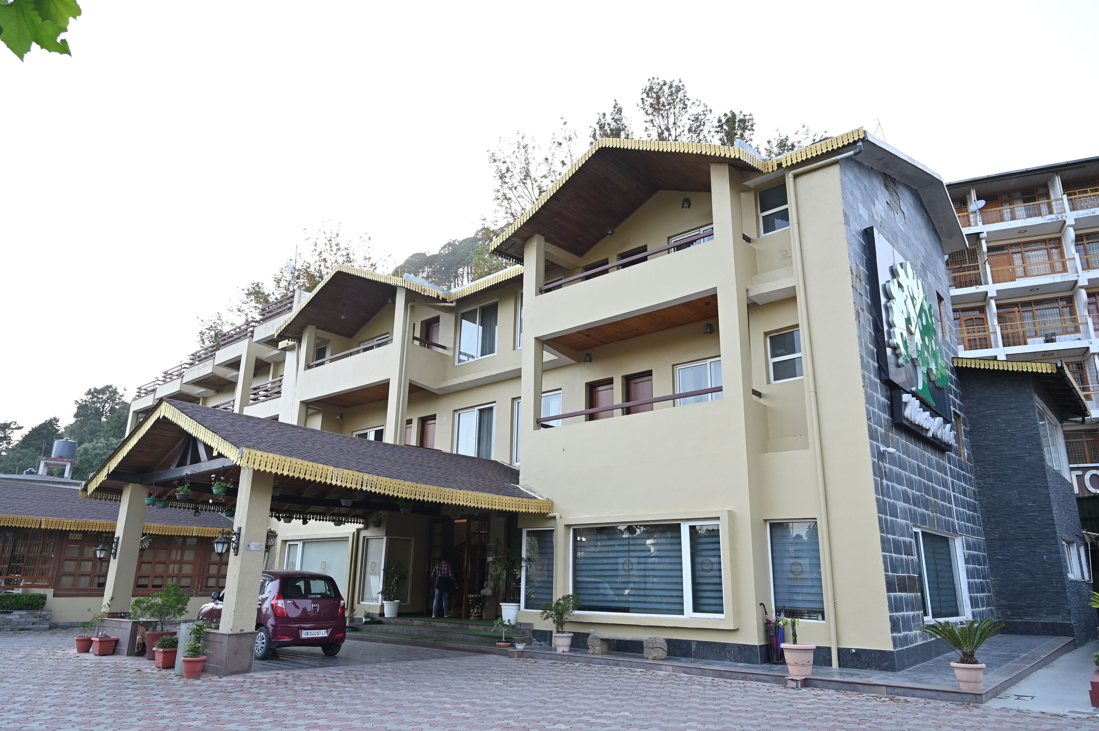 A multi-story hotel with a flat roof, balconies, and a signboard.
