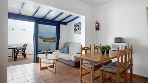 Una habitación con una mesa de comedor, sillas, un sofá, un televisor y un extintor.