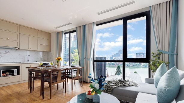 Sala de estar moderna com área de jantar, janelas amplas com vista para a cidade e cozinha com bancadas de mármore.