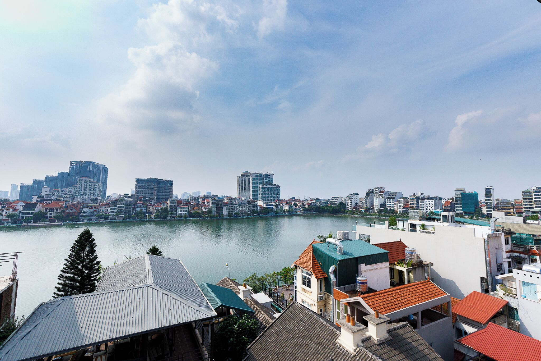 A cityscape with a river, modern buildings, and residential areas with varied roof colors.