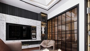 Uma sala de estar moderna com uma televisão de tela plana grande, lareira, sofá e mesa de centro com objetos decorativos.
