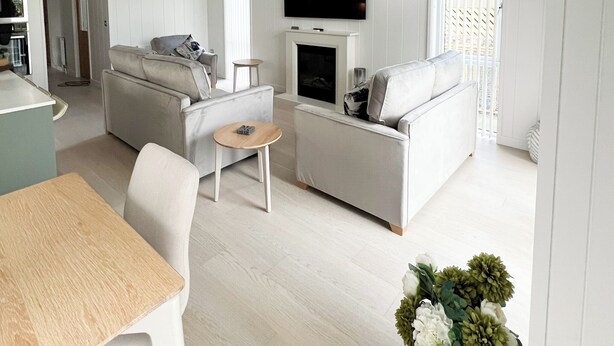 Una sala de estar moderna con un sofá, una mesita, un televisor de pantalla plana sobre la chimenea y una zona de comedor con mesa y sillas.