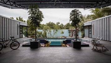 Relax by the pool surrounded by lush greenery and tall trees.