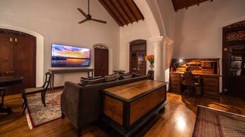 A spacious living room with a large flat-screen TV, a wooden bar area, and a cozy seating arrangement.
