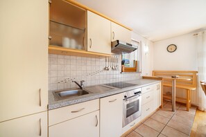 Una cocina con un lavabo, estufa y banco de madera.