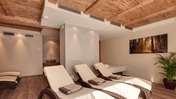 A spa room with wooden ceiling beams, a large painting of a forest, and three lounge chairs with towels. - Holiday Apartment "Sonnegg" with Mountain View, Balcony & Wi-Fi (Saltaus)