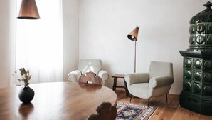 Een kamer met een houten tafel, twee stoelen, een vloerlamp, een decor kast en een kamerbreed tapijt.