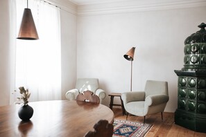 A room with a wooden table, two chairs, a floor lamp, a decorative cabinet, and a patterned rug.