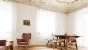 A room with a wooden dining table, chairs, a pink armchair, and a framed picture on the wall. - Apartment 'Ansitz Layshof Apt Hauskapelle' with Mountain View, Shared Garden and Wi-Fi (Merano)