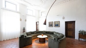 A spacious living area with a curved sectional sofa, a round coffee table, and a large window providing natural light. - Apartment 'Ansitz Layshof Apt Hauskapelle' with Mountain View, Shared Garden and Wi-Fi (Merano)