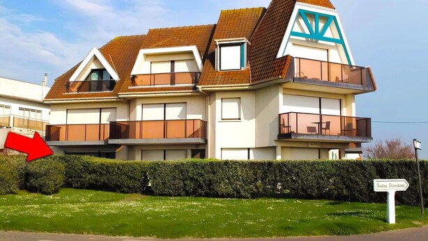 Un edificio residencial de varios pisos con un techo triangular destacado, balcones y un letrero que indica 'Tortes Directos'.