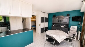Una habitación compacta con kitchenette, zona de comedor y cama.
