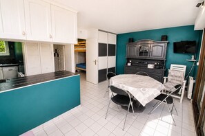 Une pièce compacte comprenant un coin cuisine, un espace repas et un lit.