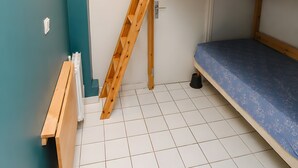 Habitación con literas, una escalera, una ventana y un radiador.