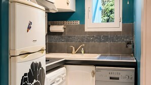 Una cocina funcional con lavadora, lavavajillas y microondas sobre la encimera.