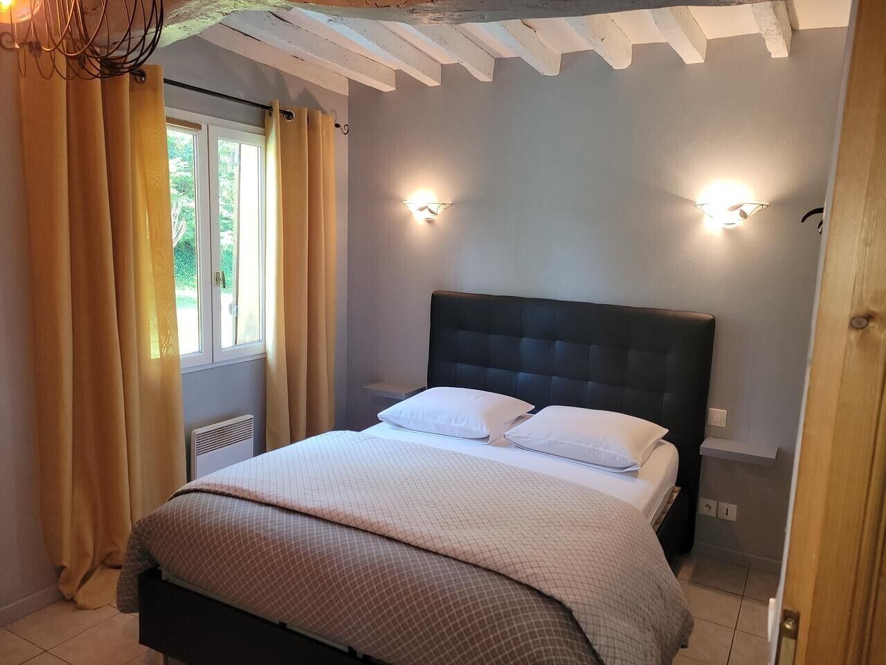 Una camera da letto con un letto, tende, una finestra e luci a parete.